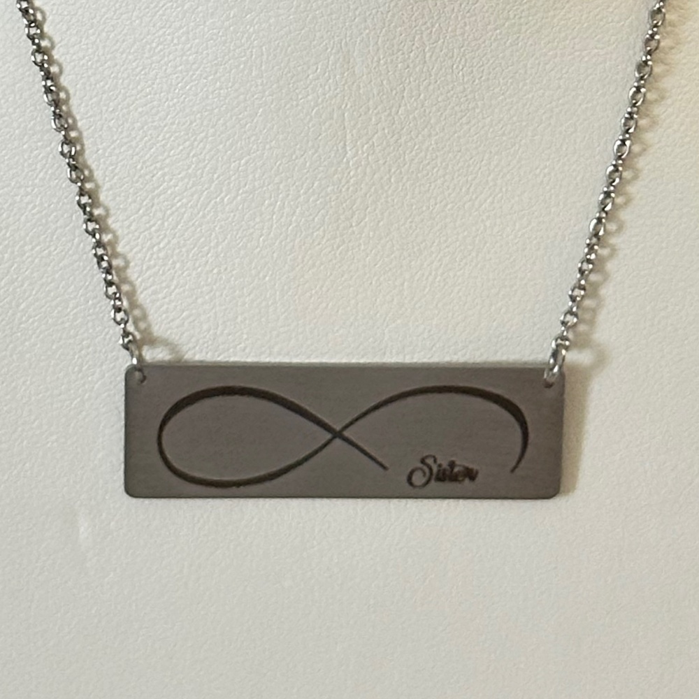 Silver tone rectangular plate on chain w/etched infinity symbol says “Sister”